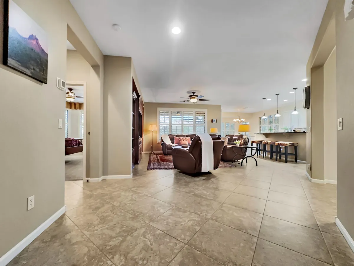 A cozy living room and kitchen bar area with inviting seating and vibrant artwork. The open space is perfect for casual socializing, relaxing, or enjoying games together. The space is warm and intimate, ideal for both quiet moments and lively gatherings.