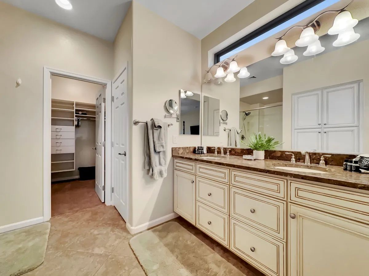 A modern bathroom with a double vanity, large mirror, soft lighting, and a plant on the counter. The ambiance is calm and inviting, ideal for daily routines or relaxation after a busy day.