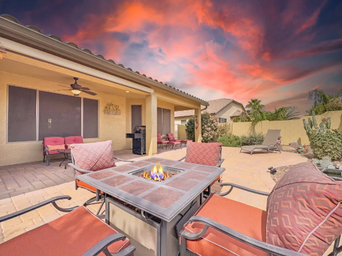 This image features a beautifully landscaped backyard garden with a central fire pit surrounded by inviting outdoor seating. The setting is designed for relaxation and gatherings, with lush greenery and a warm, ambient glow from the fire, capturing the essence of cozy evenings outdoors.