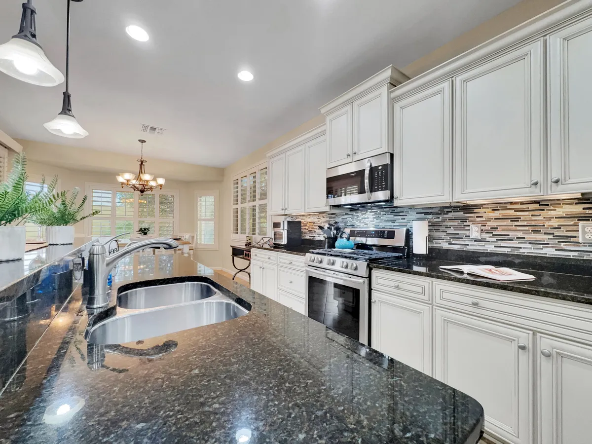 A modern kitchen with granite countertops, stainless steel appliances, pendant lighting, and a view of the outdoor space. The open-plan layout makes it ideal for cooking, entertaining, and connecting with guests or family.