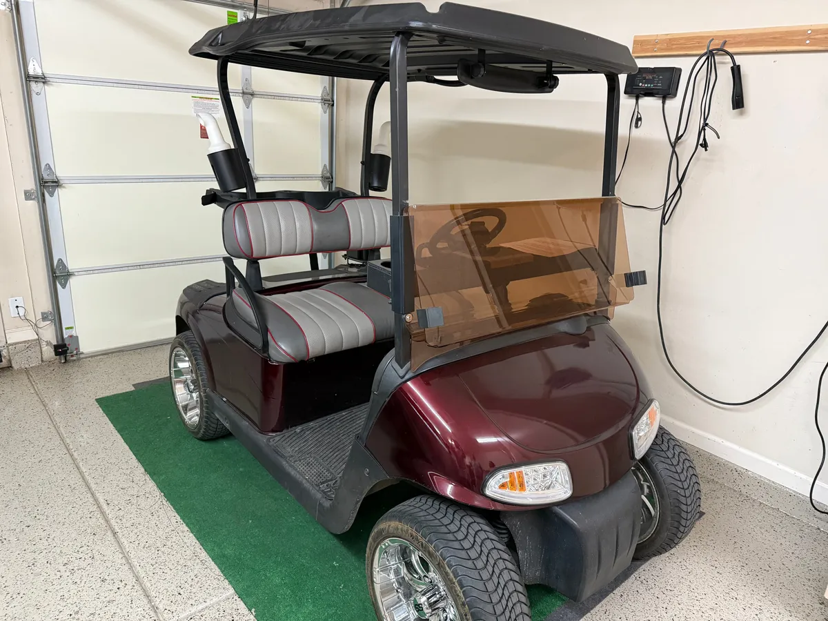 This image captures a golf cart inside a garage, signaling easy access to neighborhood amenities and local attractions. The green mat and practical garage details add a sense of daily life and readiness for adventure.