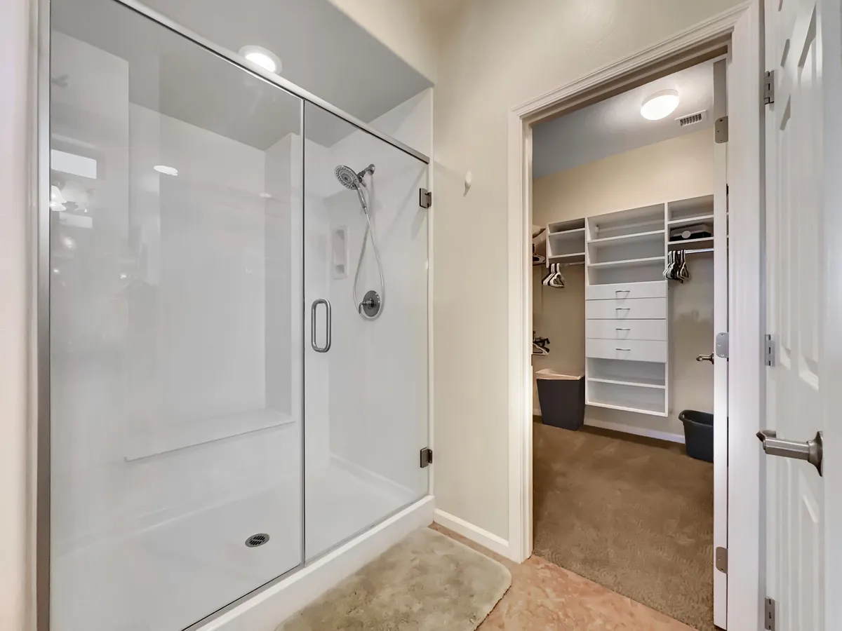 A fresh, organized bathroom featuring a glass shower and walk-in closet, offering ample storage and a streamlined grooming space. The bright, uncluttered design ensures easy routines and a settled-in feel.